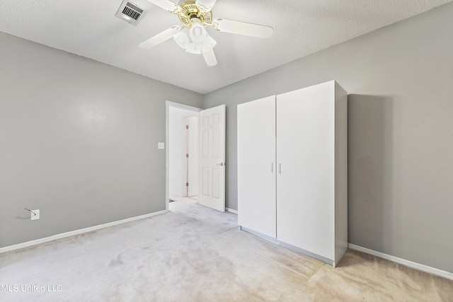 unfurnished bedroom with light carpet, a closet, a textured ceiling, and ceiling fan