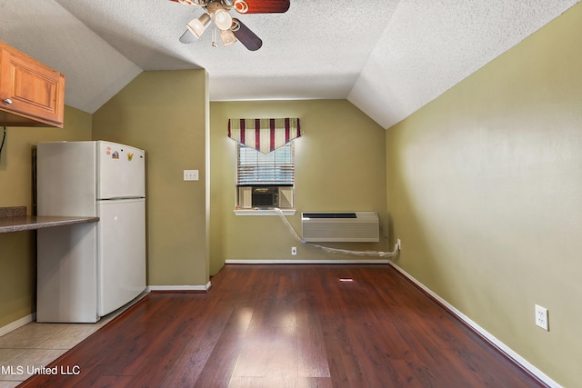 kitchen with lofted ceiling, a textured ceiling, hardwood / wood-style flooring, a wall mounted air conditioner, and white fridge