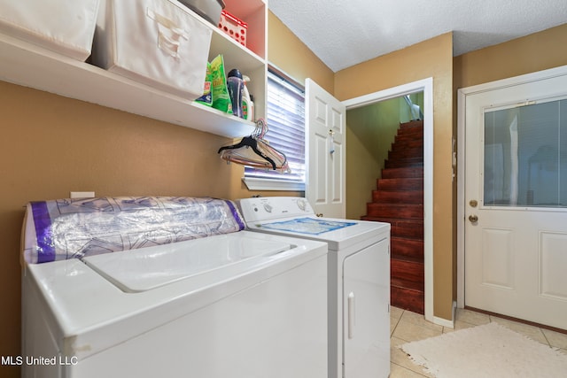 clothes washing area featuring a textured ceiling, washing machine and clothes dryer, and light tile patterned floors