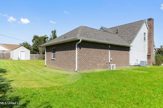 back of property featuring a storage shed, a yard, and central AC unit