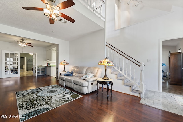 living room with dark hardwood / wood-style floors, a textured ceiling, a high ceiling, and ceiling fan