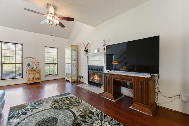 living room featuring a textured ceiling, vaulted ceiling, dark hardwood / wood-style floors, and ceiling fan