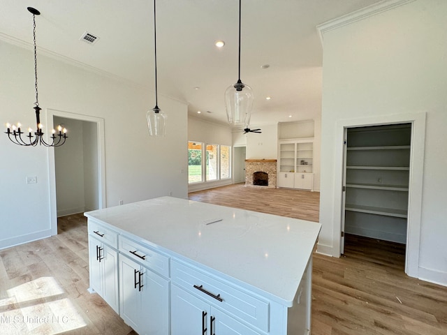 kitchen featuring a center island, decorative light fixtures, white cabinetry, and light hardwood / wood-style flooring