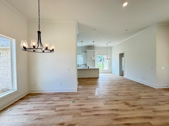 unfurnished dining area featuring crown molding, light hardwood / wood-style flooring, and a chandelier