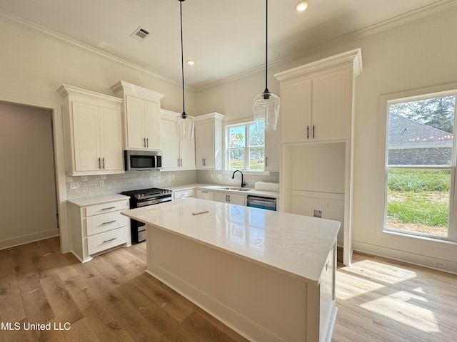 kitchen with pendant lighting, stainless steel appliances, a kitchen island, and white cabinetry