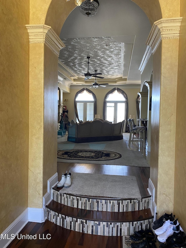 foyer featuring arched walkways, hardwood / wood-style floors, a textured wall, and ceiling fan