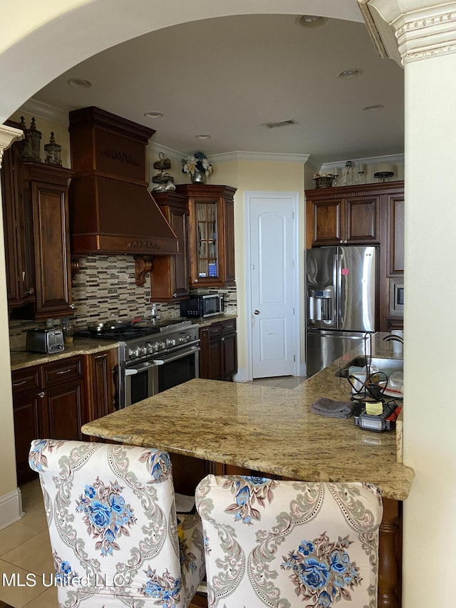 kitchen with a sink, visible vents, custom range hood, crown molding, and appliances with stainless steel finishes