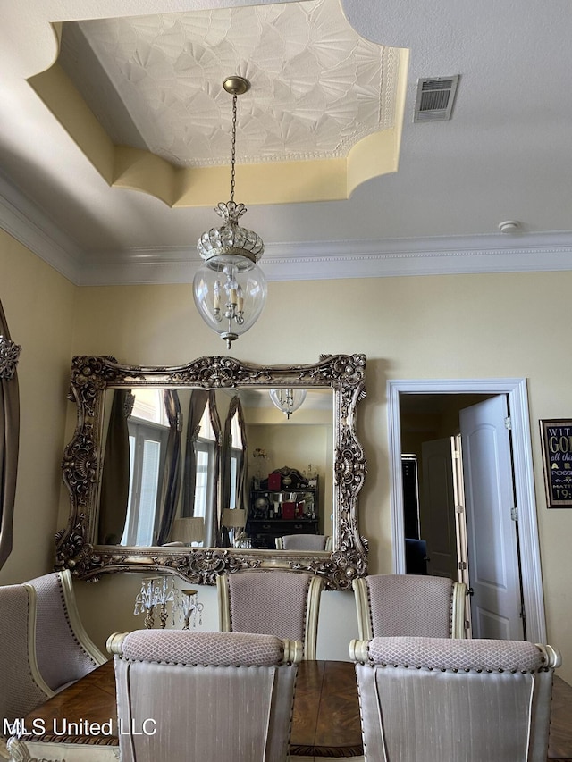 dining room featuring dark wood-style floors, ornamental molding, visible vents, and a raised ceiling