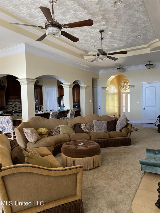 living area featuring a ceiling fan, arched walkways, carpet, ornamental molding, and decorative columns