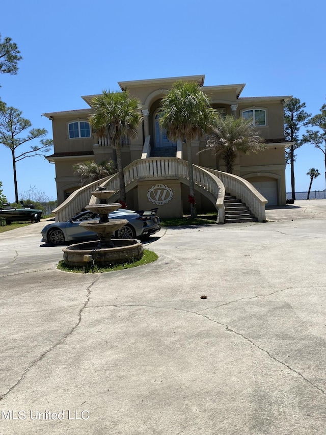 view of front facade with an attached garage, stairs, and stucco siding