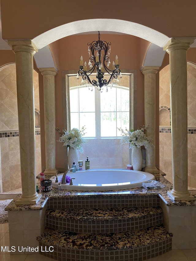 bathroom featuring a bath, tile patterned floors, an inviting chandelier, and ornate columns