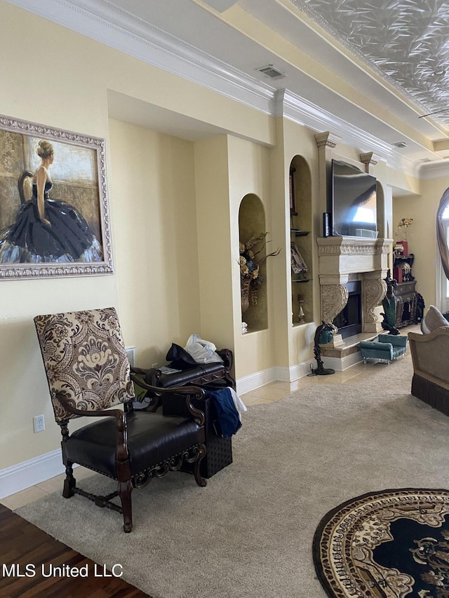sitting room with a tray ceiling, a premium fireplace, crown molding, and baseboards
