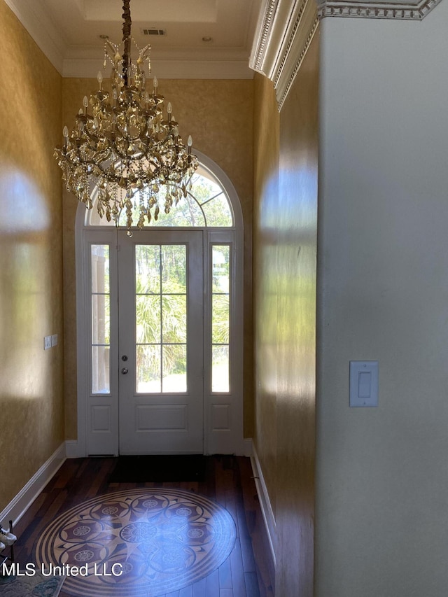 foyer entrance with a wealth of natural light, ornamental molding, a chandelier, and dark wood-type flooring