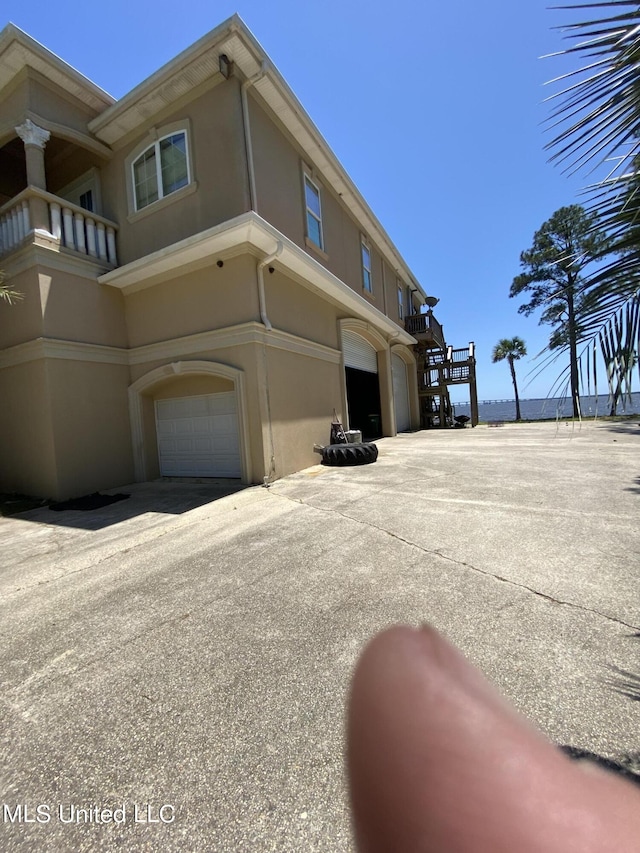 view of side of home with an attached garage, stucco siding, and driveway