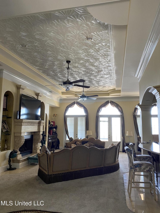 carpeted living room with ceiling fan, a fireplace, ornamental molding, and a raised ceiling