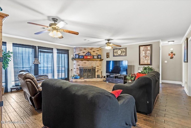 living room featuring baseboards, ceiling fan, ornamental molding, wood finished floors, and a fireplace