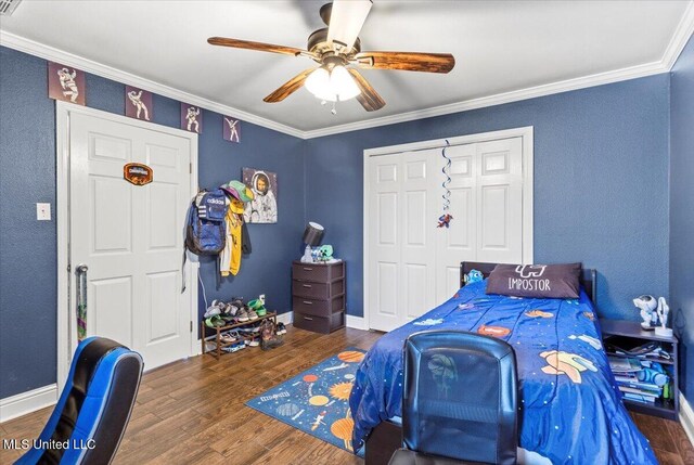 bedroom with baseboards, a ceiling fan, wood finished floors, crown molding, and a closet