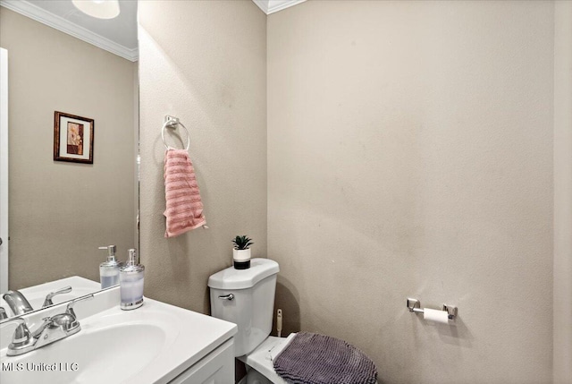 half bath with ornamental molding, vanity, and toilet