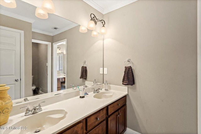 bathroom featuring double vanity, ornamental molding, a sink, and toilet