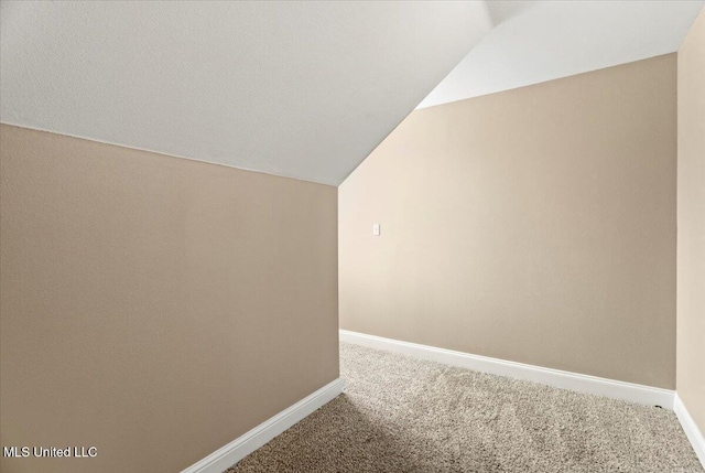 corridor with vaulted ceiling, carpet, and baseboards