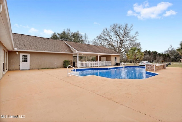 outdoor pool featuring fence and a patio