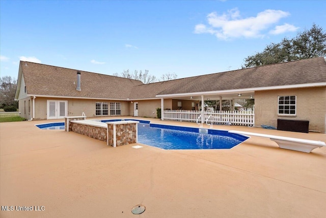 pool featuring french doors, a patio, a hot tub, fence, and a diving board