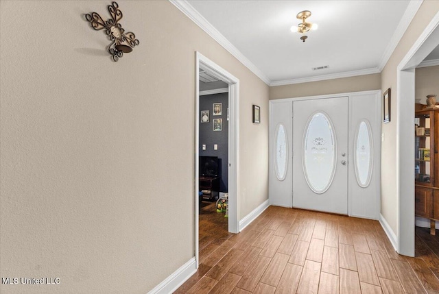 entryway featuring baseboards, crown molding, visible vents, and wood finished floors