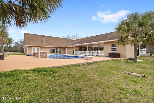 rear view of property with an outdoor pool, a patio area, and a yard