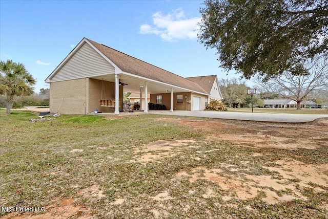 exterior space featuring driveway, ceiling fan, an attached garage, and a yard