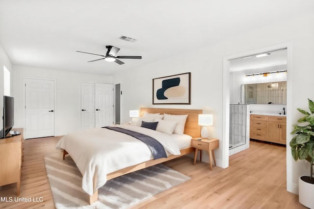 bedroom featuring ceiling fan, light hardwood / wood-style flooring, ensuite bathroom, and sink