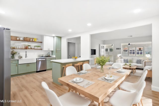 dining space with ceiling fan, light hardwood / wood-style floors, and sink