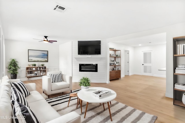 living room with a fireplace, light hardwood / wood-style floors, and ceiling fan