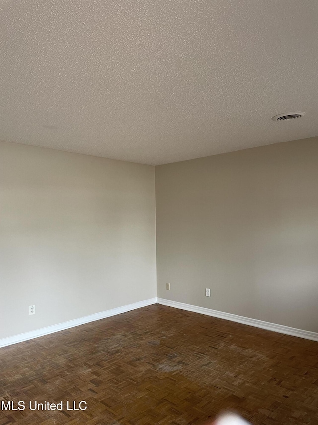 spare room with dark parquet floors and a textured ceiling