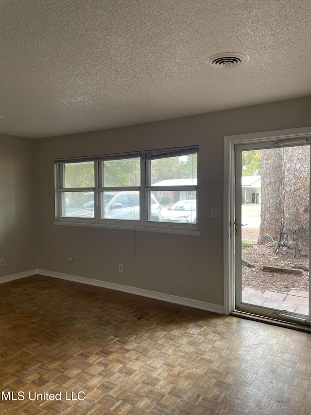 spare room with parquet flooring and a textured ceiling