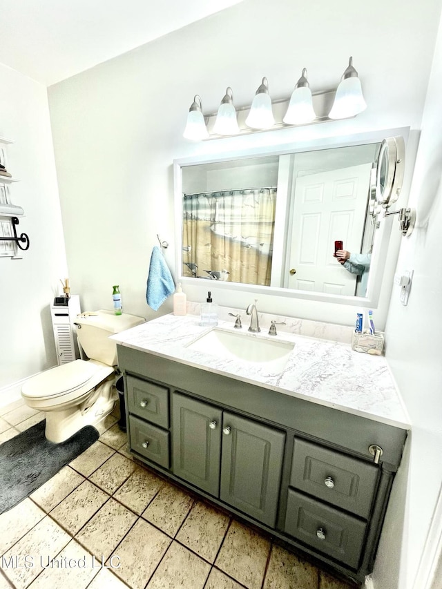 bathroom with toilet, a shower with curtain, vanity, and tile patterned floors