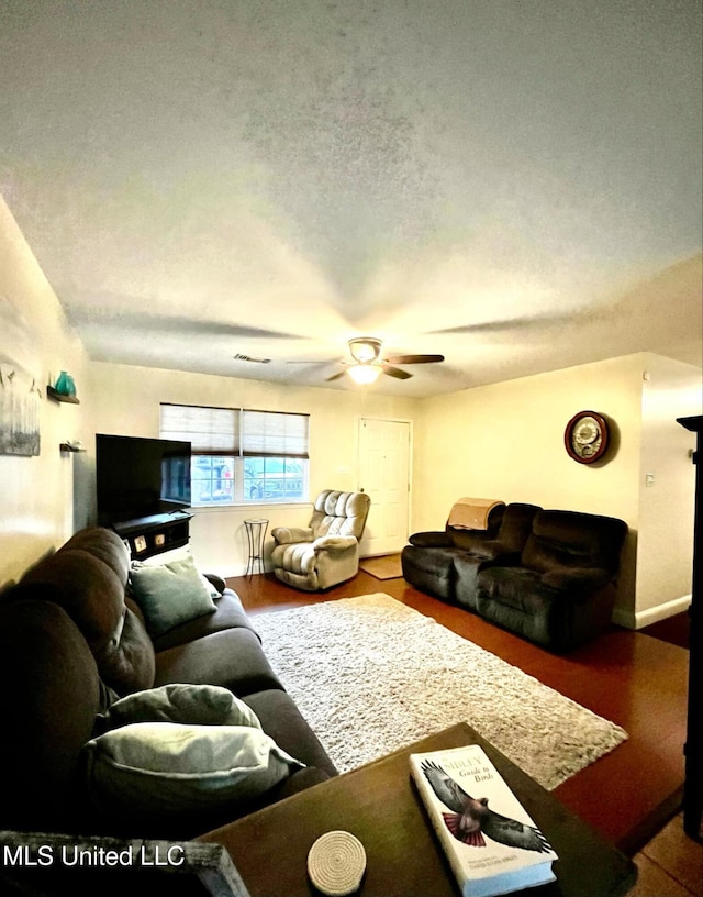 living room featuring ceiling fan, a textured ceiling, and wood finished floors