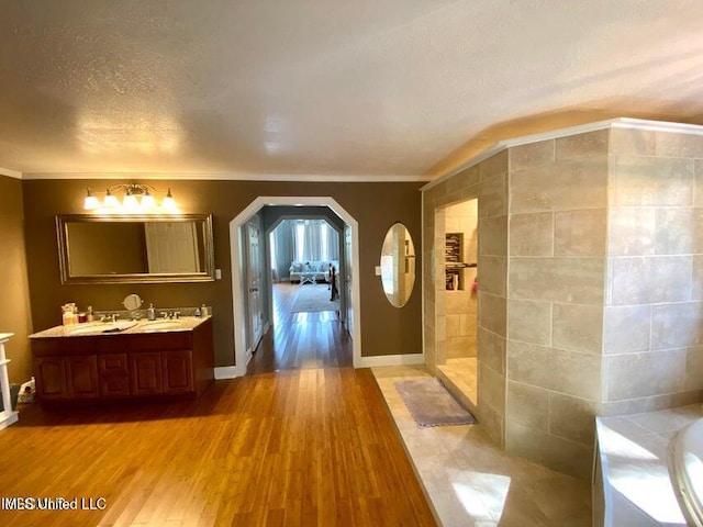 20507 Old Biloxi Rd, Vancleave, MS 39565 - full bathroom with wood finished floors, double vanity, a garden tub, a textured ceiling, and ornamental molding