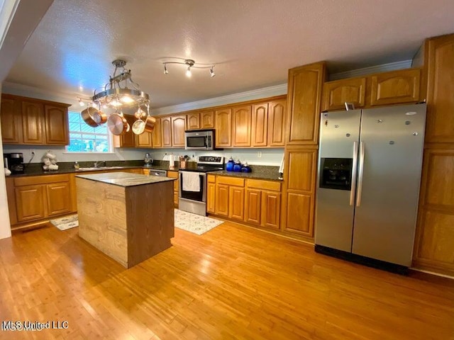 20507 Old Biloxi Rd, Vancleave, MS 39565 - kitchen featuring appliances with stainless steel finishes, brown cabinetry, light wood finished floors, a center island, and ornamental molding