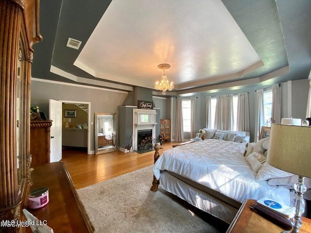 20507 Old Biloxi Rd, Vancleave, MS 39565 - bedroom with a tray ceiling, multiple windows, a chandelier, and wood finished floors