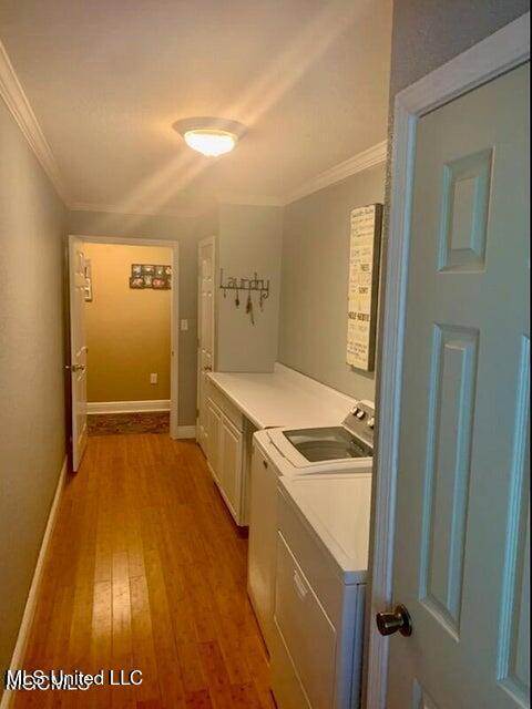 20507 Old Biloxi Rd, Vancleave, MS 39565 - washroom with cabinet space, crown molding, washing machine and clothes dryer, and light wood-type flooring