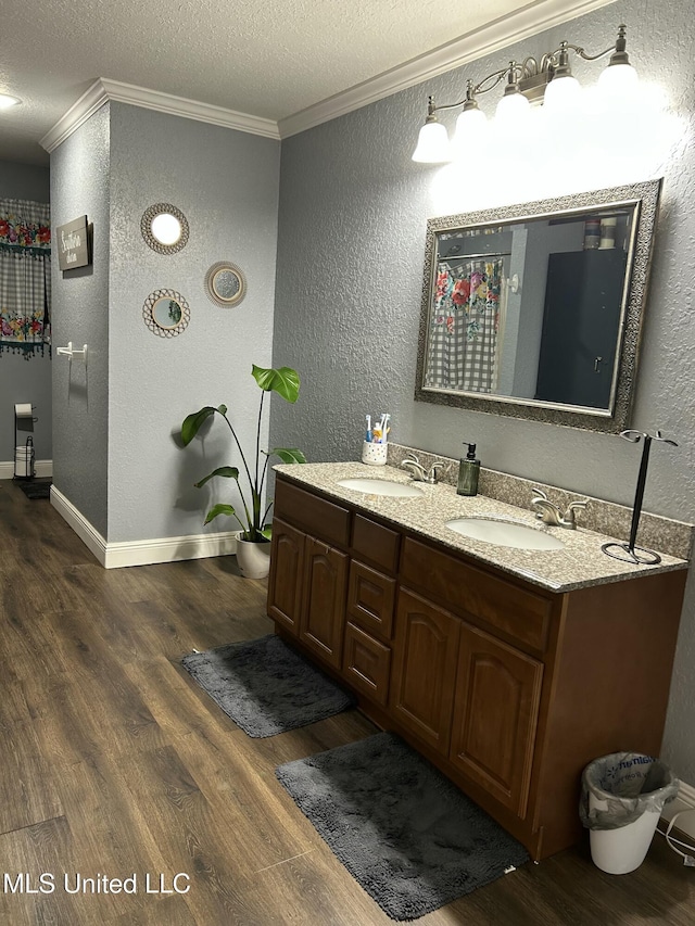 20507 Old Biloxi Rd, Vancleave, MS 39565 - bathroom with ornamental molding, a textured wall, wood finished floors, double vanity, and a textured ceiling
