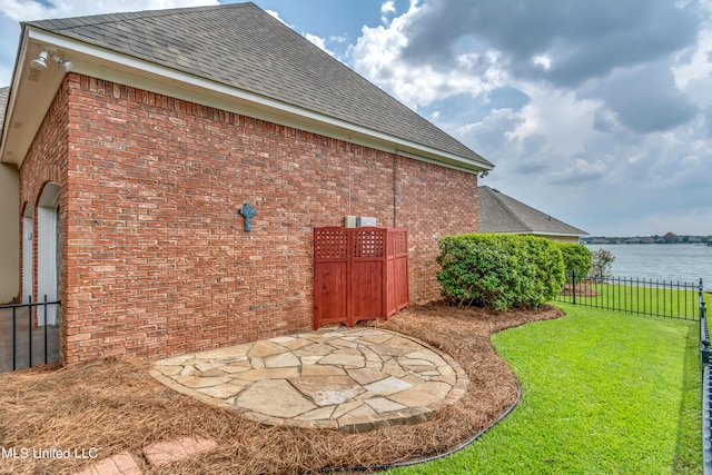 exterior space with a water view, a patio area, and a lawn