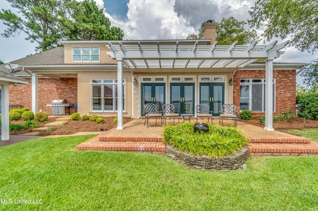 back of property with a pergola, a patio area, and a lawn