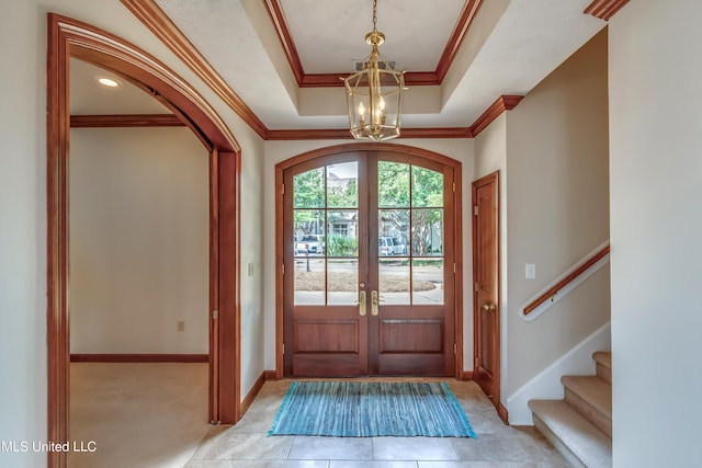 foyer entrance with ornamental molding, french doors, a chandelier, and a raised ceiling