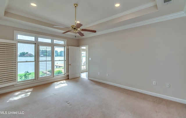 spare room with ornamental molding, light colored carpet, and a tray ceiling