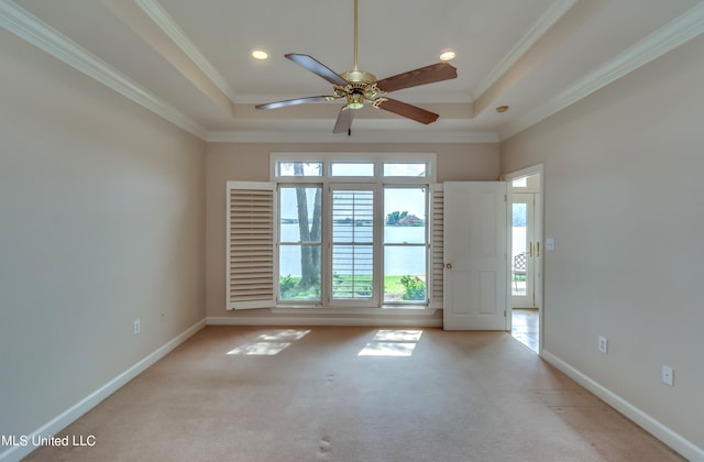 carpeted spare room with ornamental molding, a raised ceiling, and ceiling fan