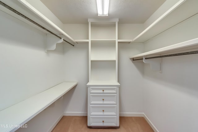 walk in closet featuring light colored carpet