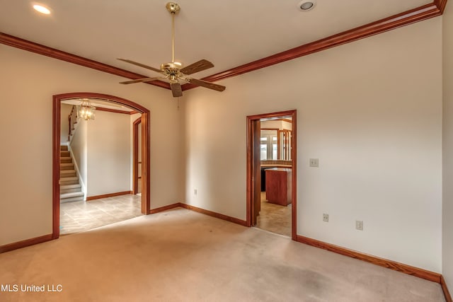 carpeted spare room featuring crown molding and ceiling fan