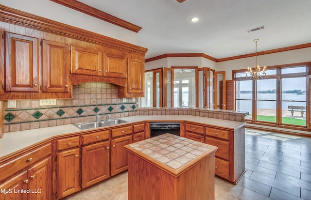 kitchen featuring dishwasher, hanging light fixtures, sink, a center island, and a water view