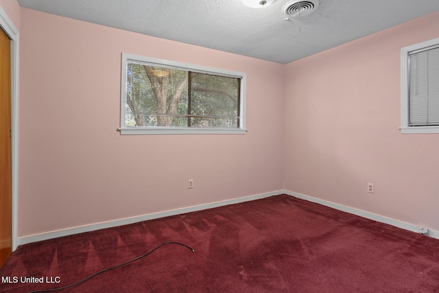 carpeted empty room featuring a textured ceiling